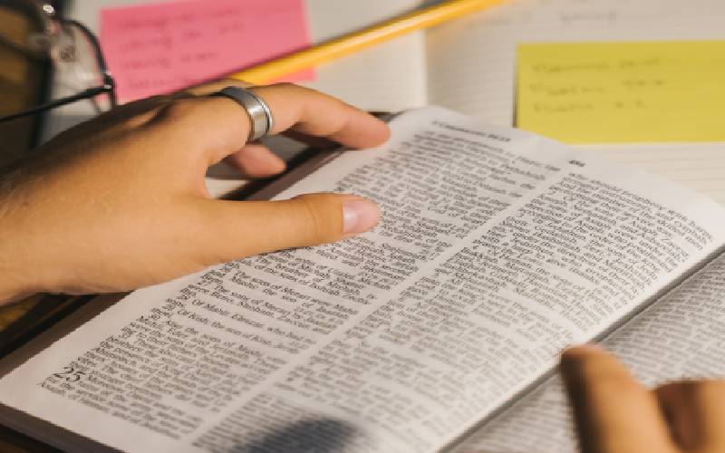 A person is reading the newspaper with their hand on it.