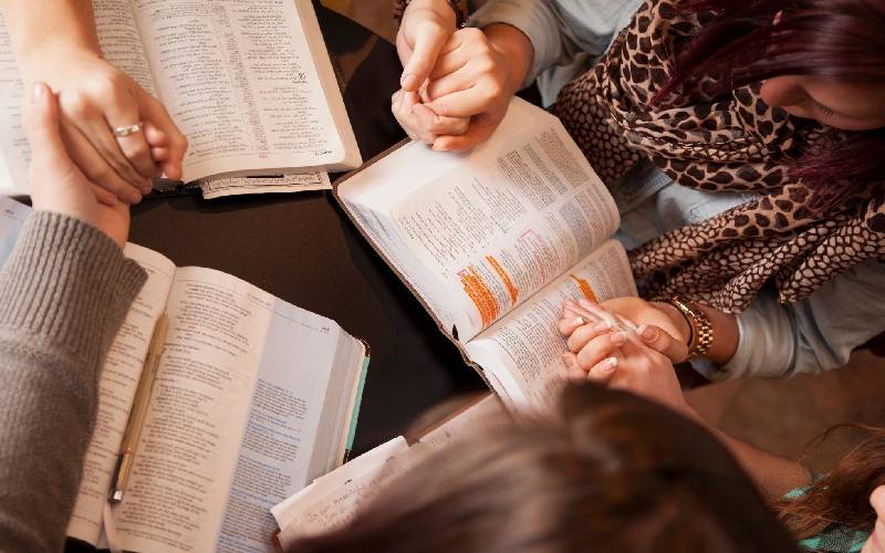 A group of people sitting around each other reading.