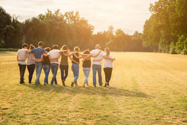 A group of people standing in the grass with their hands around each other.