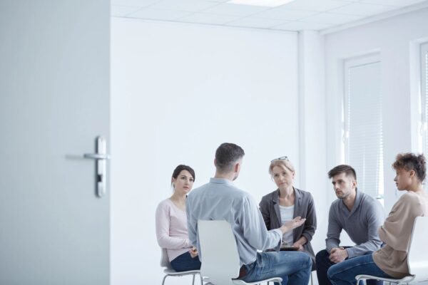 A group of people sitting in chairs talking to each other.