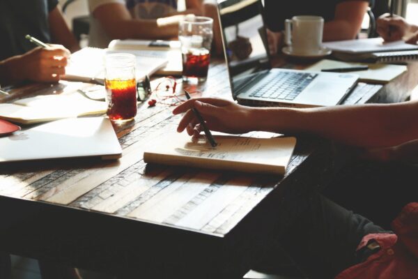 A person is writing on a notebook at a table.